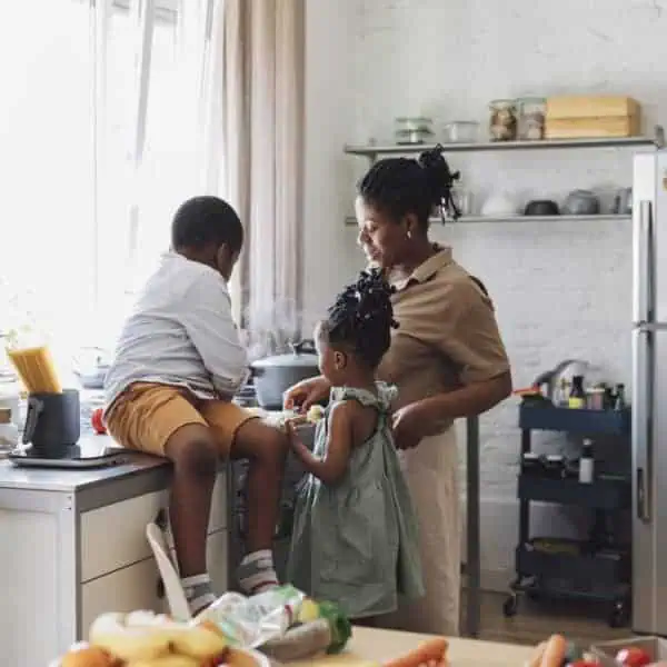Happy mother, daughter and son preparing vegetables for lunch over a kitchen sink.