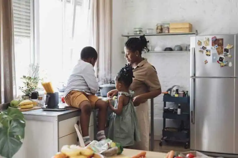 Happy mother, daughter and son preparing vegetables for lunch over a kitchen sink.